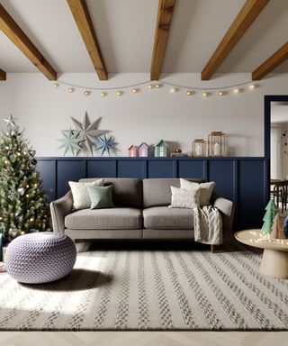 A gray couch next to a Christmas tree, coffee tbale, and a blue sideboard with colorful houses