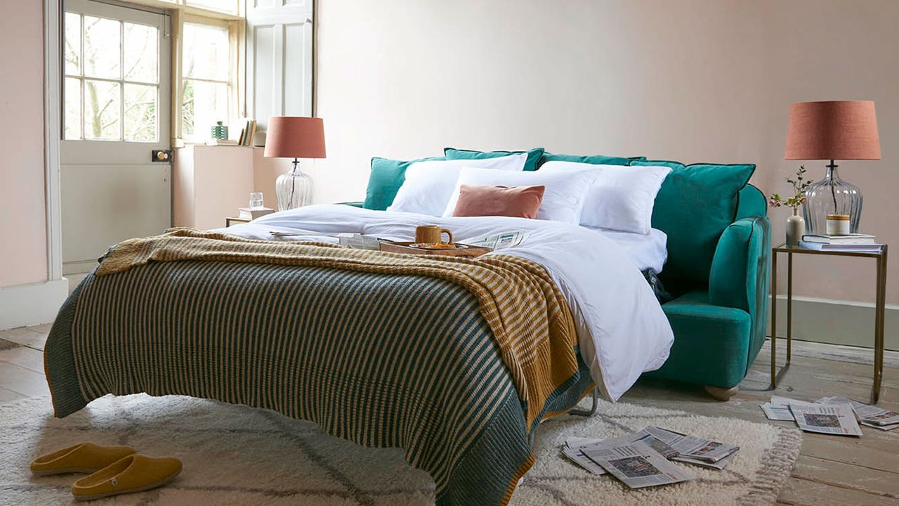 Teal sofa bed in white room with yellow blanket