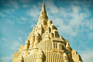 A giant sandcastle with a blue sky overhead.