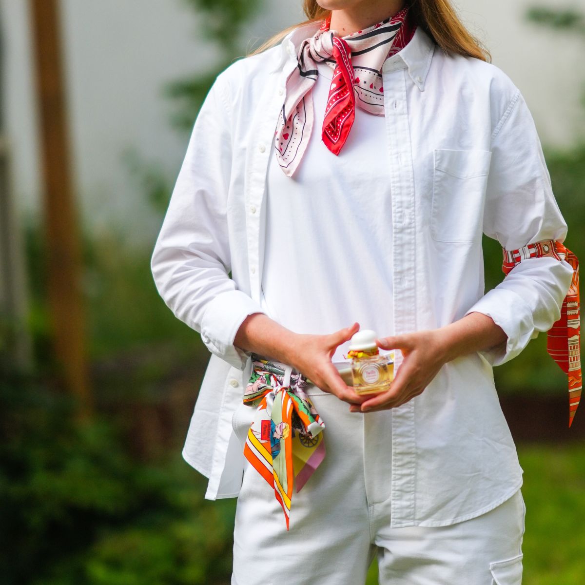 woman in white outfit holding a perfume bottle