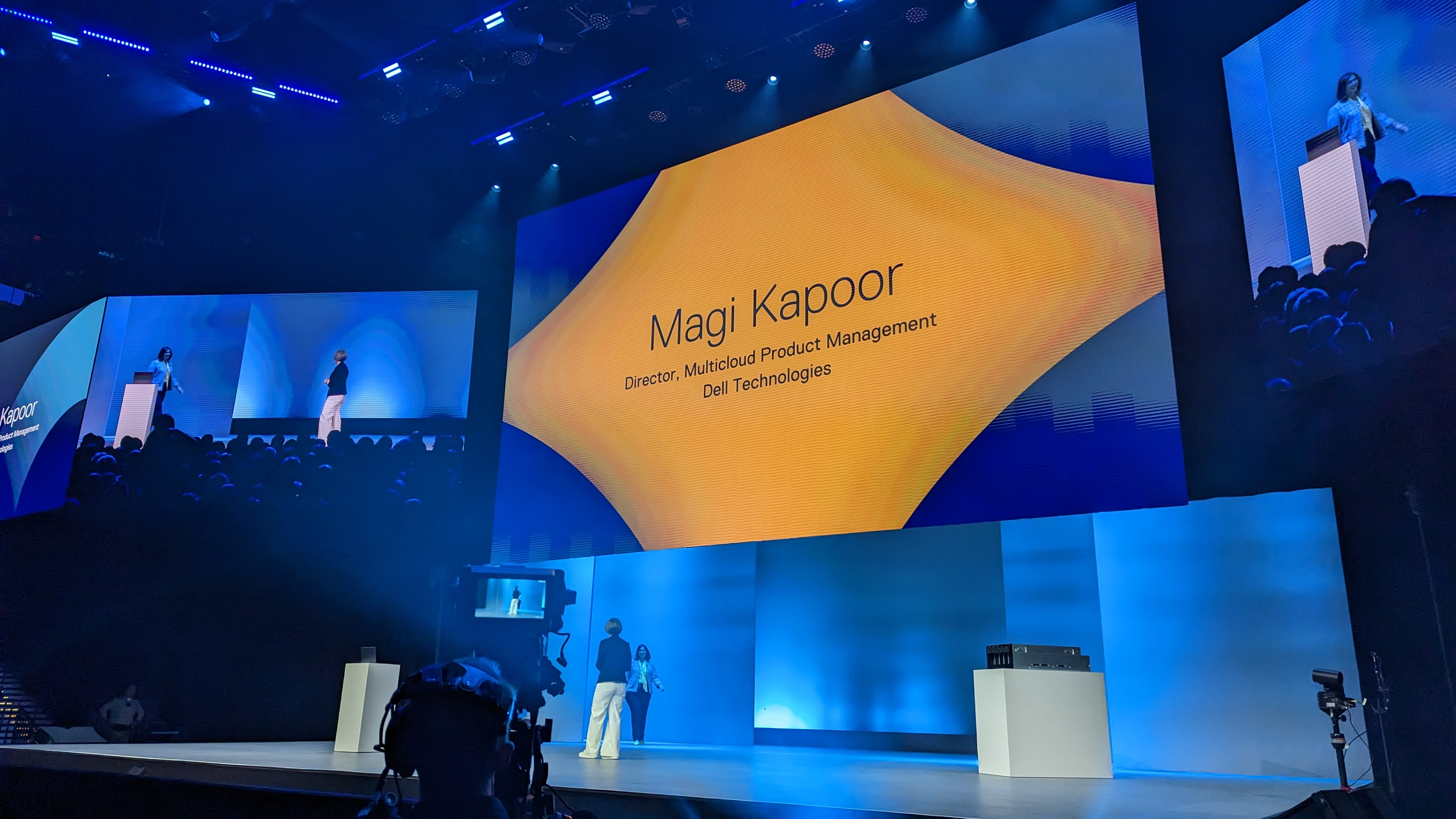 A screen that reads 'Magi Kapoor, Director, Multicloud Product Management Dell Technologies'' on an orange stylised diamond shape, with Dell chief digital officer and CIO Jen Felch welcoming Magi Kapoor onto the keynote stage at Dell Technologies World 2023.