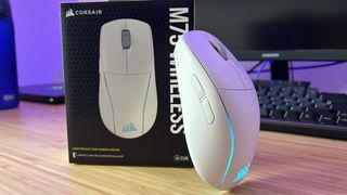 Corsair M75 Wireless gaming mouse leaning against the product box on a wooden desk