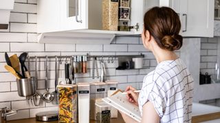 Young woman making a note of kitchen supplies