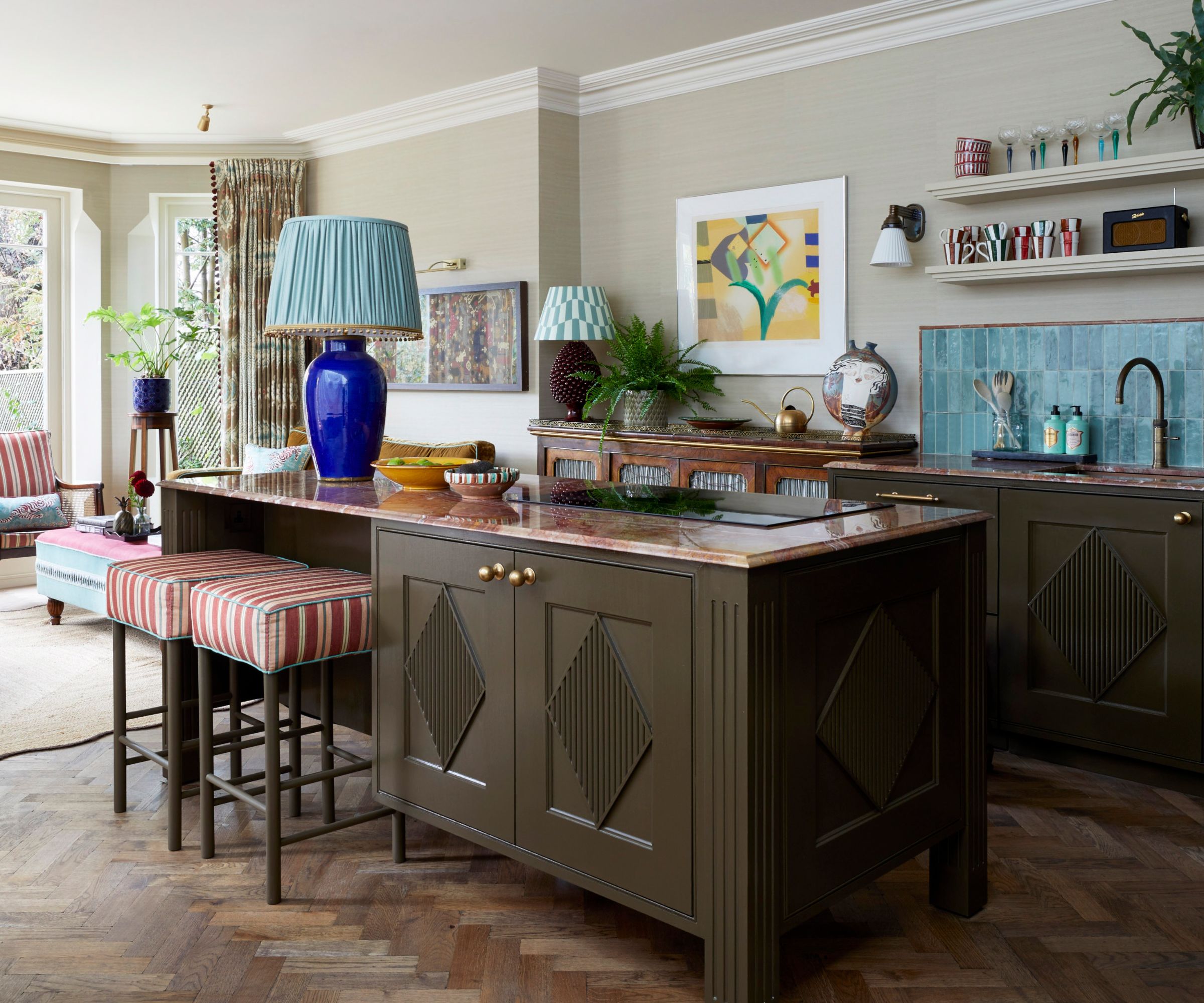 An open plan kitchen with green cabinetry and island with brown marble countertops