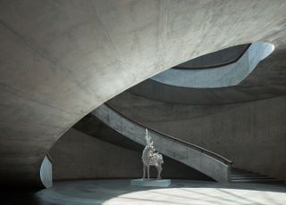 Interior of the He Art Museum. All concrete building, with a sculpture of a deer next to the spiral staircase.