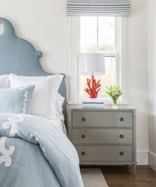 light blue and white coastal bedroom with coral accent lamp