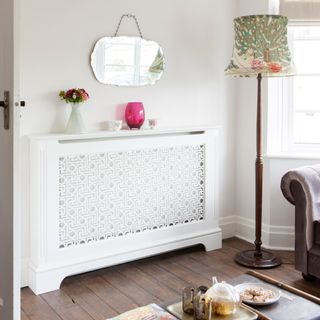 White radiator cover with patterned screen in living room with wooden floor