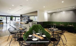 The dining area consists of square, black tables and chairs with green upholstery