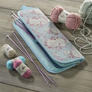 wooden table with knitting needle yarn and printed blue bag