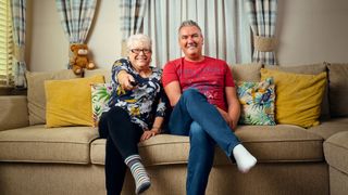 Jenny Newby and Lee Riley on a cream sofa with yellow cushions