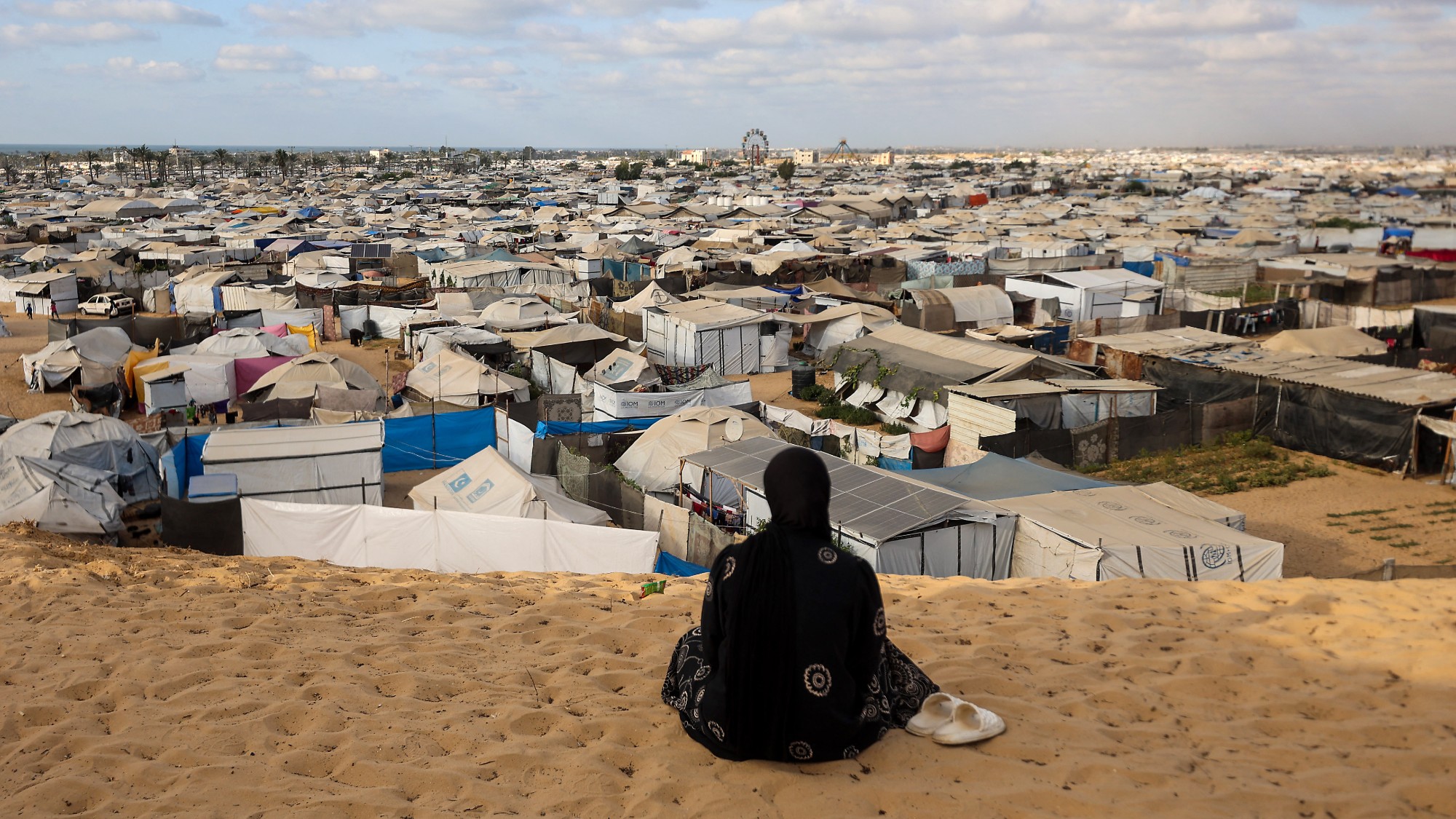 A Palestinian woman sits overlooking a camp for displaced people in Khan Yunis in the southern Gaza