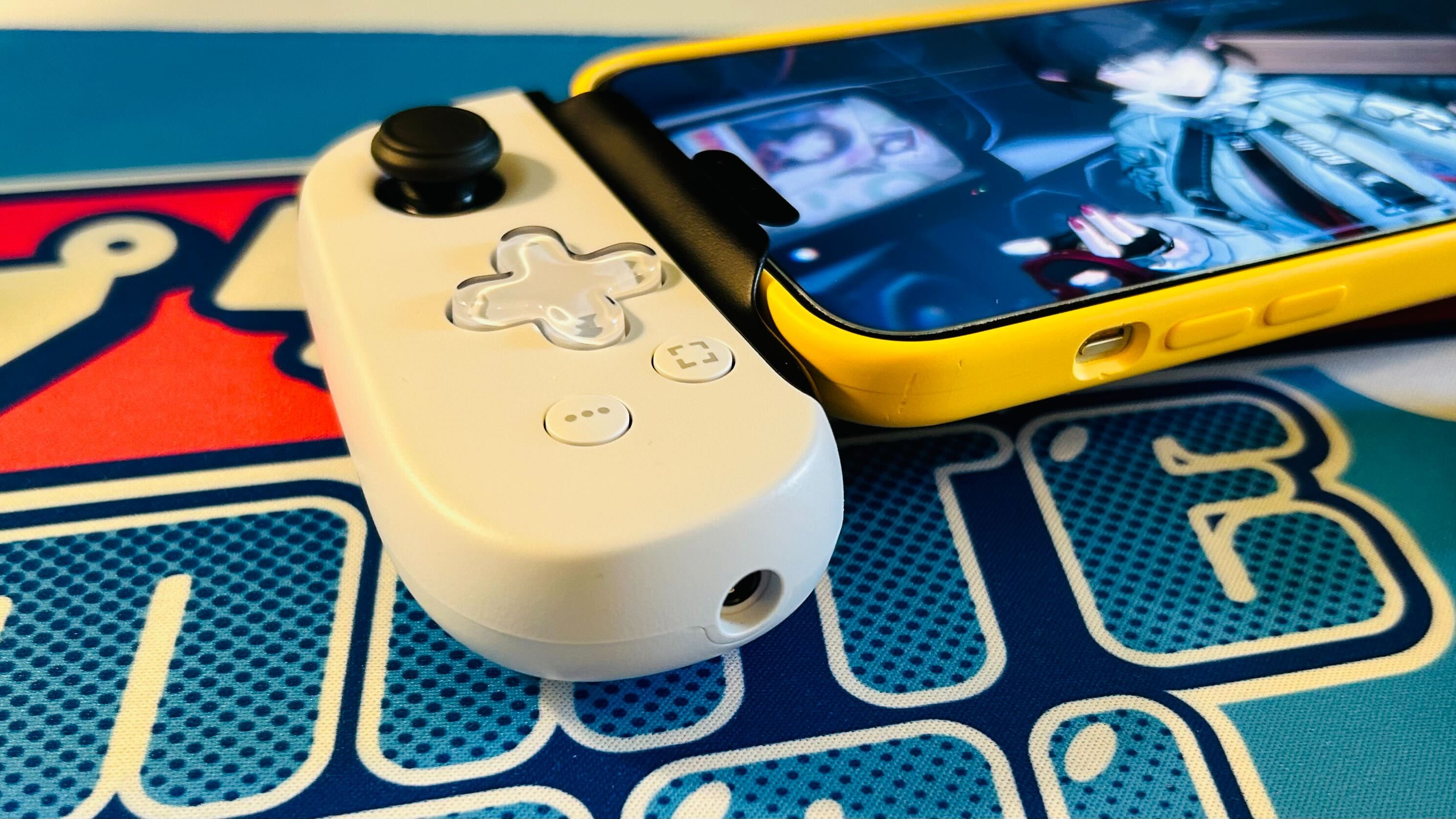 The left hand grip of the Backbone One 2nd Gen PlayStation Edition on a bright blue desk mat.