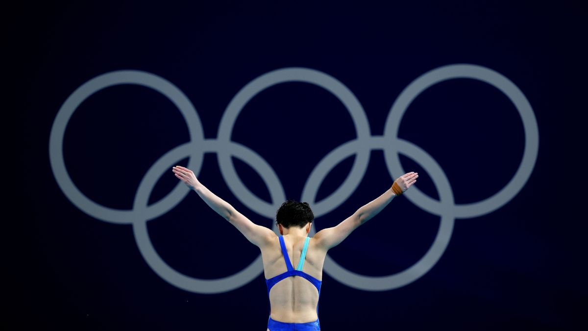 Yiwen Chen preparing a dive before the Olympic ring symbol.