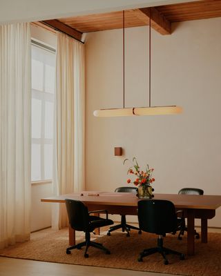 minimalist dining room with long glass pendant light over the table