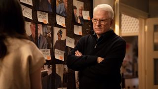 Steve Martin stands in front of a photo board in Only Murders in the Building