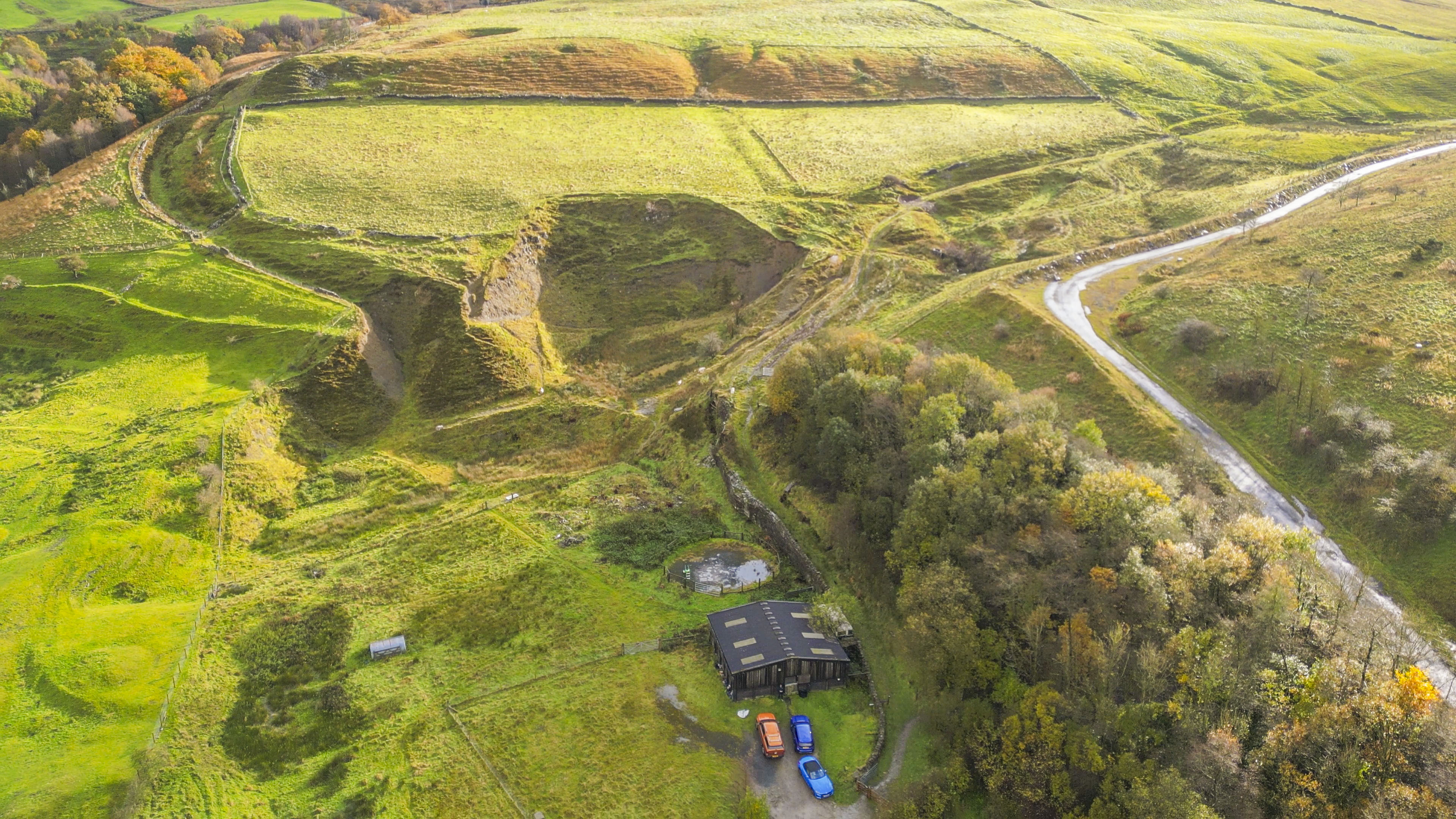 A barn and paddocks set into a hilly landscape.