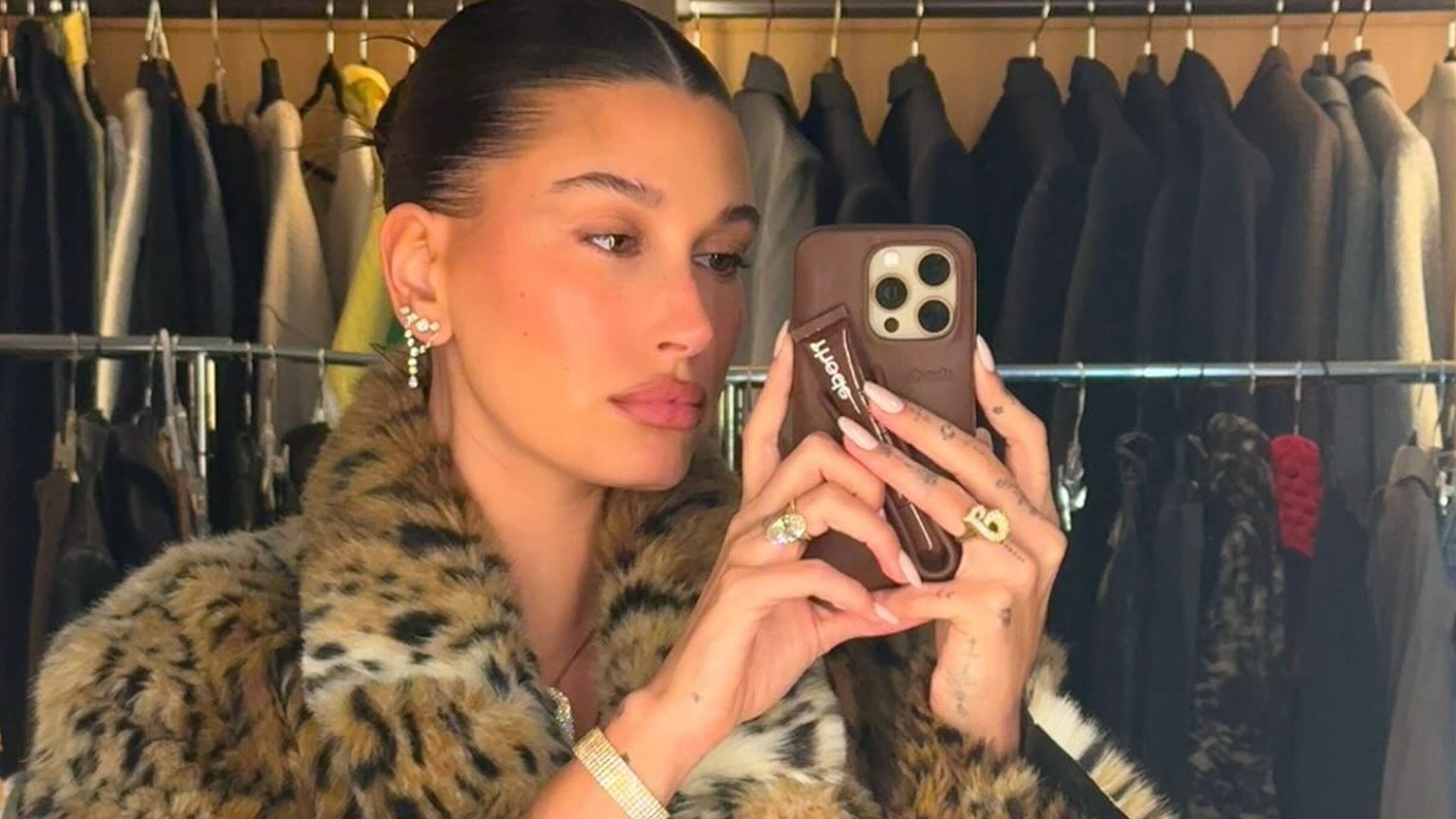Hailey Bieber in her closet wearing a leopard print fur jacket.