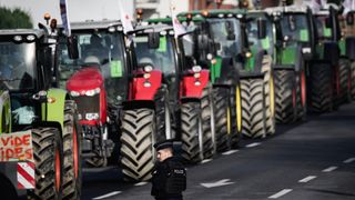 Farmers drive past police in their tractors as part of a demonstration against agricultural policy in Rennes, western France