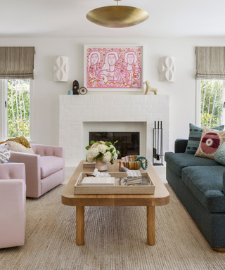 A wooden coffee table surrounded by two pink armchairs and a blue couch.