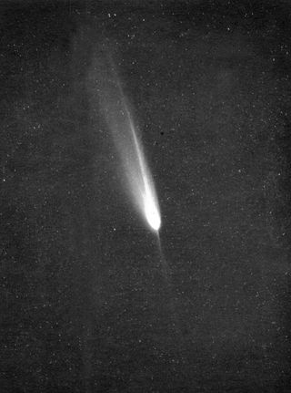 A black and white image, mostly black, witha white glowing orb in the center, with a tail streaking upward to the left.