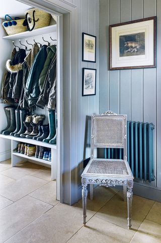 bootroom with grey cladding walls blue traditional radiator and grey painted cane chair and coats on pegs