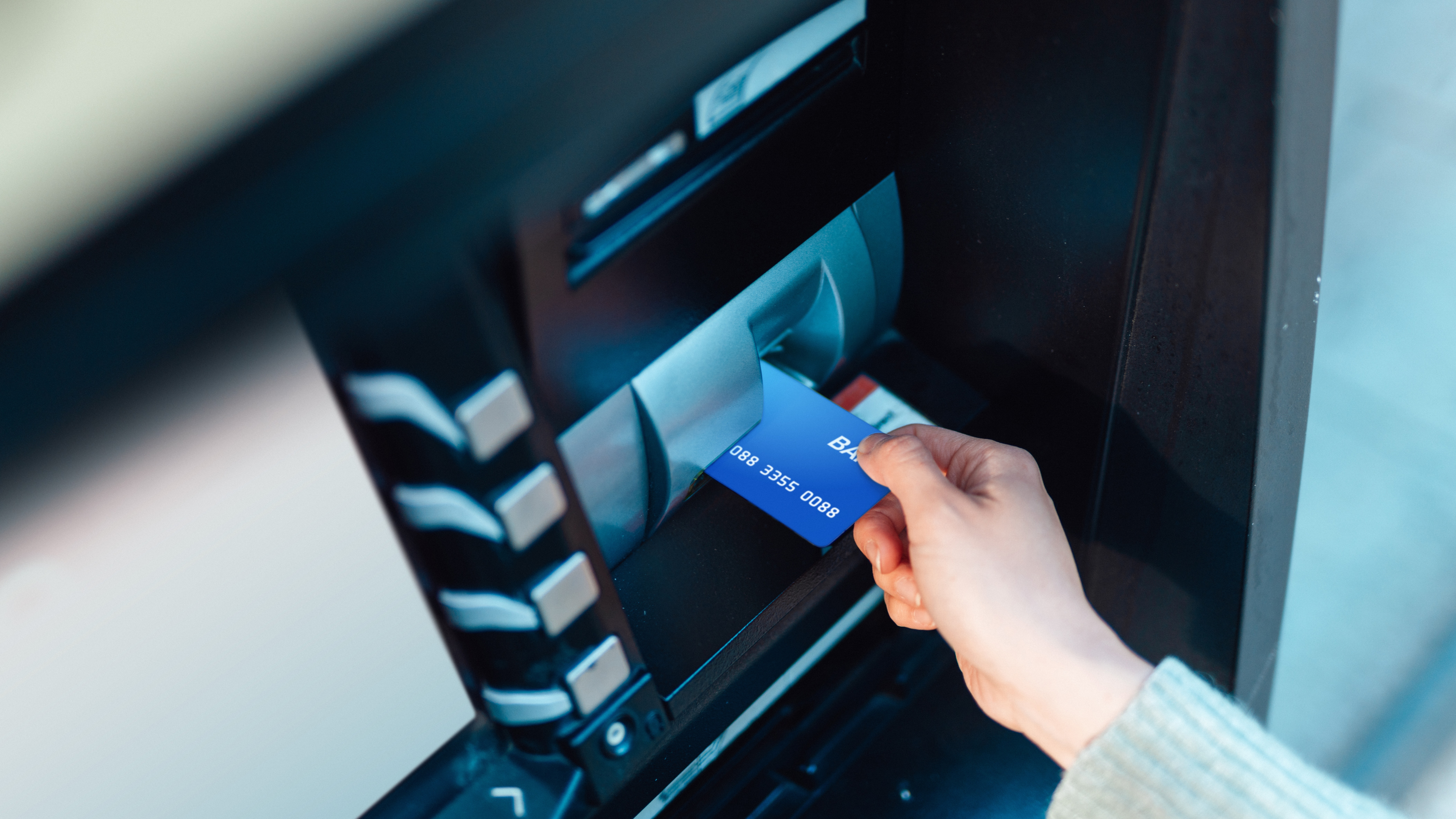 A woman putting her card into an ATM.