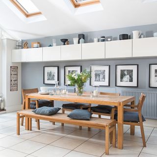 grey dining room with wooden table, framed photographs and storage