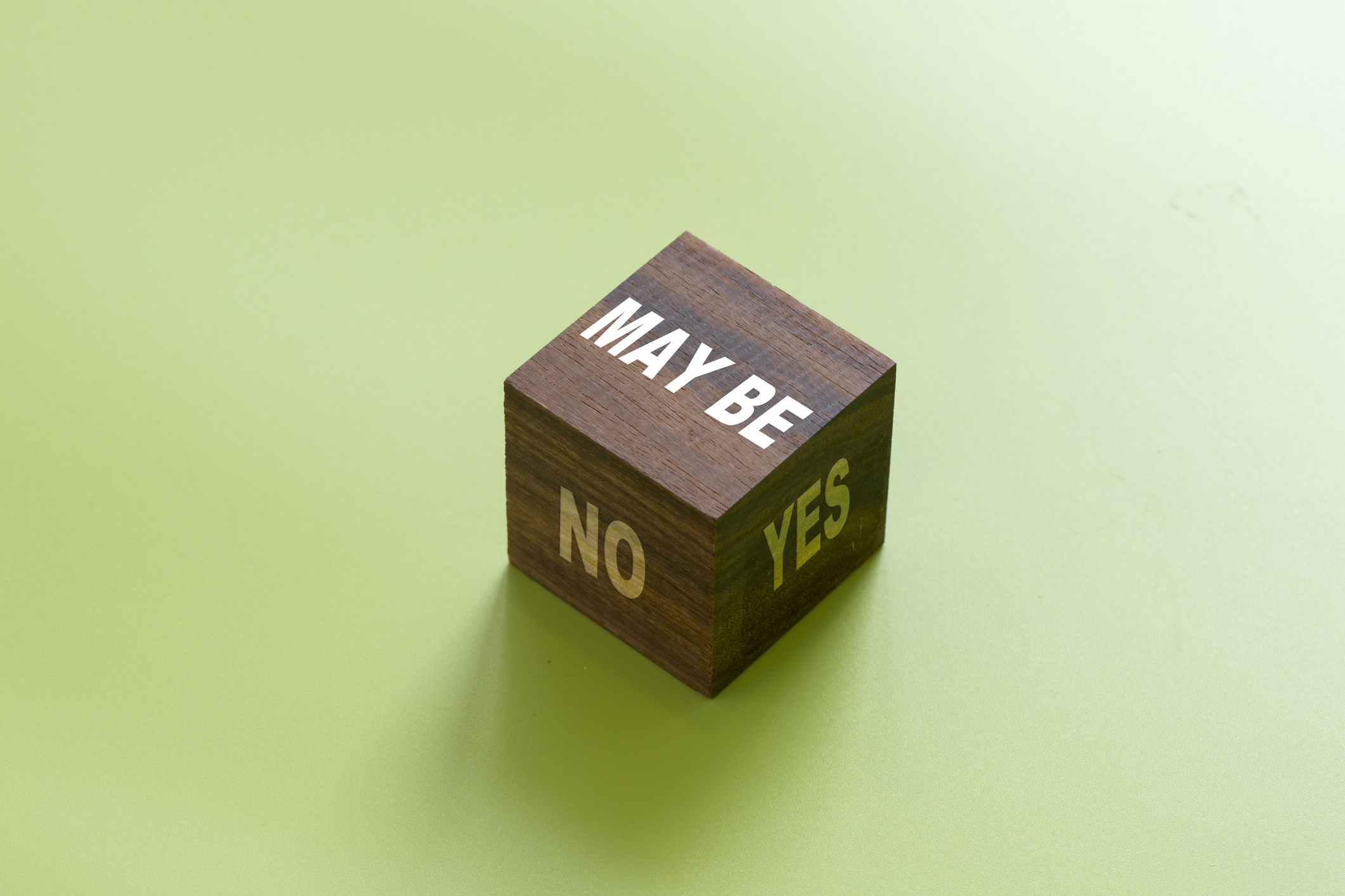 Wooden dice with &quot;Yes, No and May Be&quot; printed close up shot.