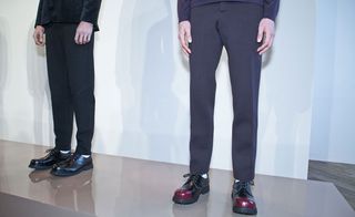 Two pairs of legs stood a few feet apart, wearing smart trousers and shoes with their hands creeping into the frame