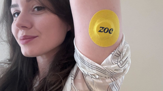 Josephine Watson, Managing Editor of Lifestyle at TechRadar, holding her arm up to show the attached Zoe CGM