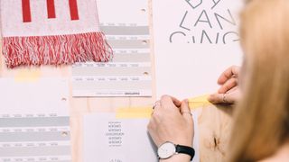 An artist affixing a length of tape to their work