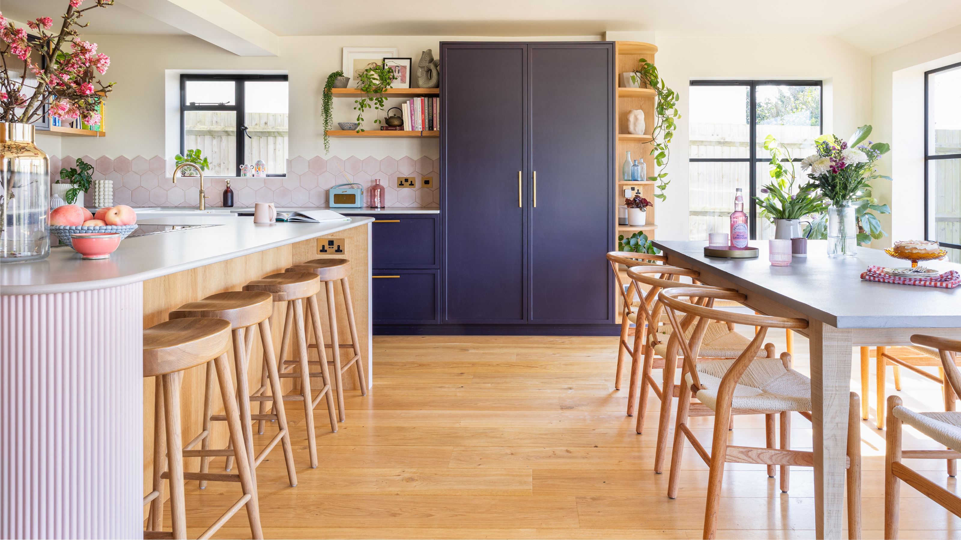 Kitchen-diner with wooden floors, blue fitted cabinetry and a wooden kitchen island and dining room table