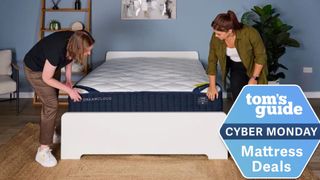 The image shows two women unboxing a navy blue and white mattress, which is placed on a white bed frame against a blue wall. On the top of the image a badge reads 'Tom's Guide Cyber Monday Mattress Deals'