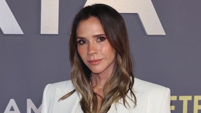Victoria Beckham is pictured with wavy hair and wearing a white blazer whilst attending the "Victoria Beckham" World Premiere at the Curzon Mayfair on October 08, 2025 in London, England.