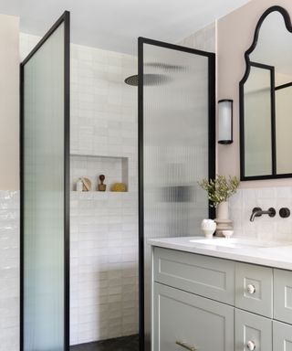 A white bathroom with a walk-in shower surrounded by a fluted glass partition screen