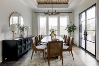 A black credenza with white lamps and plants on top positioned behind a dining room table