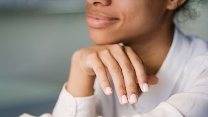 Manicure and pedicure tools - image of a woman with her chin on the back of her hand showing her beautiful nails - gettyimages1468504863
