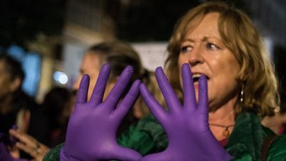 A woman with violet hands protesting over the ‘wolf pack’ case