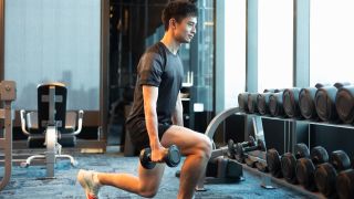 Man performs lunge with dumbbells in a gym