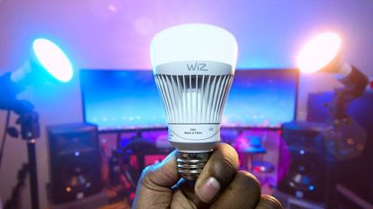 Someone holding up a Wiz smart bulb
