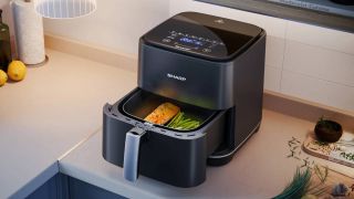 An open Sharp air fryer sitting on a kitchen counter with food inside the baskets