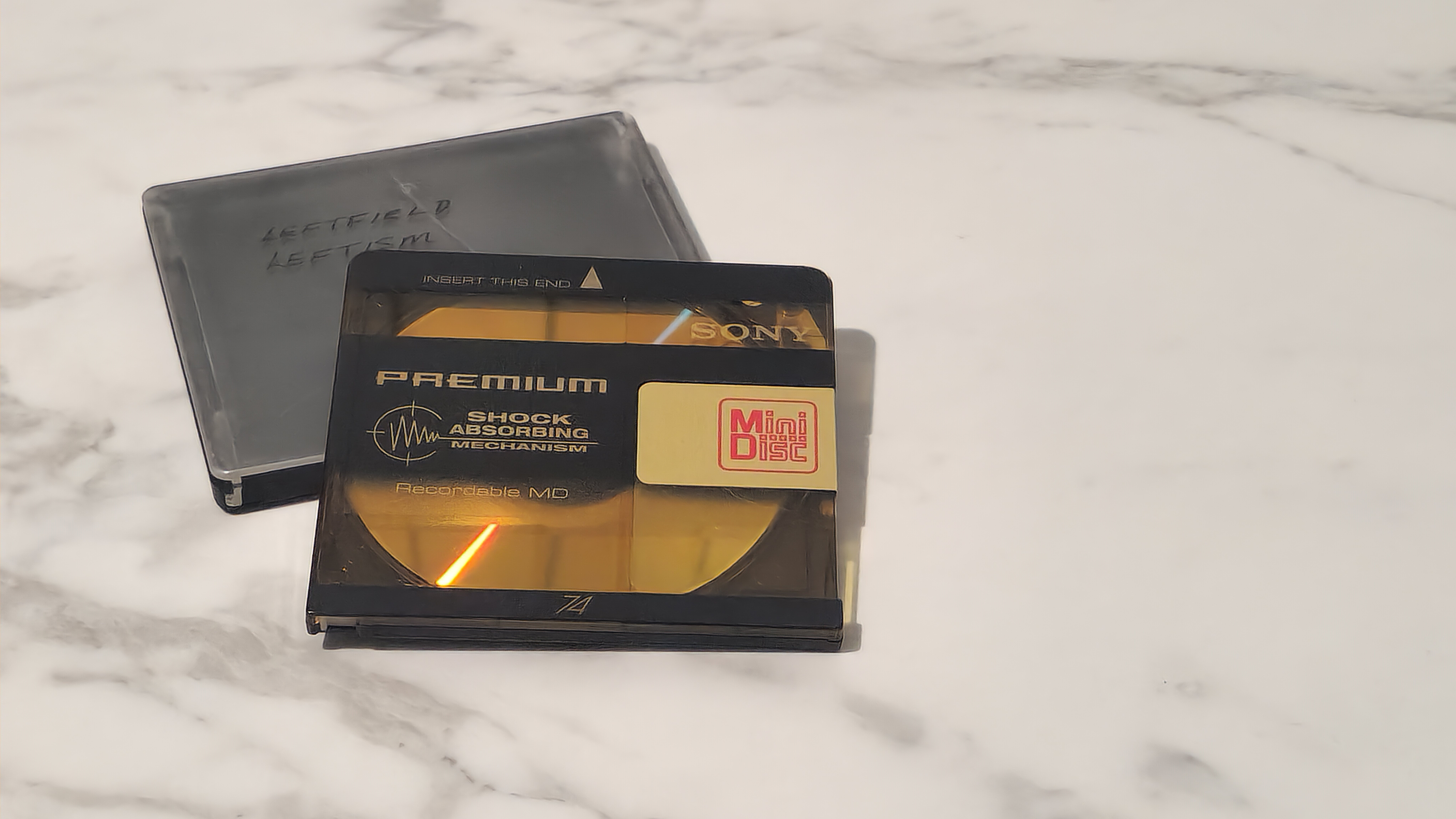 MiniDisc and case on white marble surface