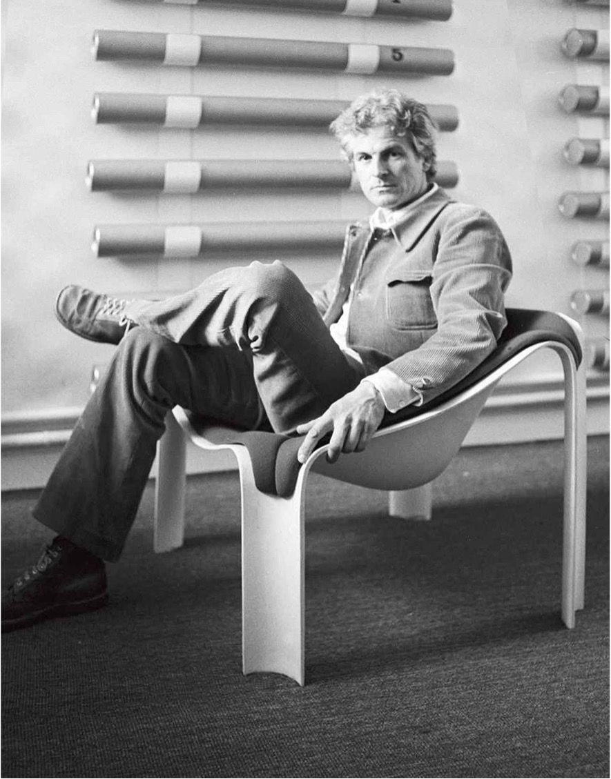 casually dressed man sits on futuristic plastic moulded lounge chair