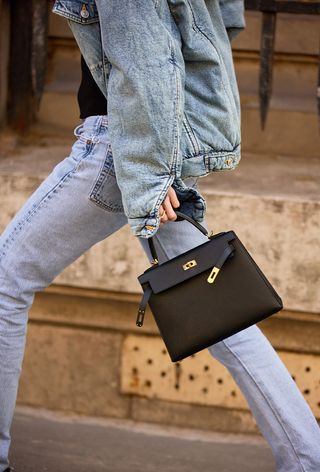 a street-style photo of a woman wearing a vintage Hermes bag styled with an all-denim outfit