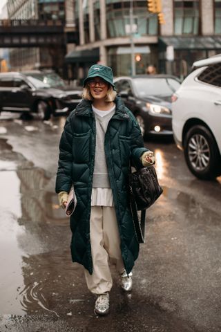 woman wearing green coat, grey sweater, baggy pants