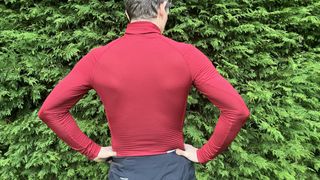 Rear view of man in long-sleeved base layer by hedge