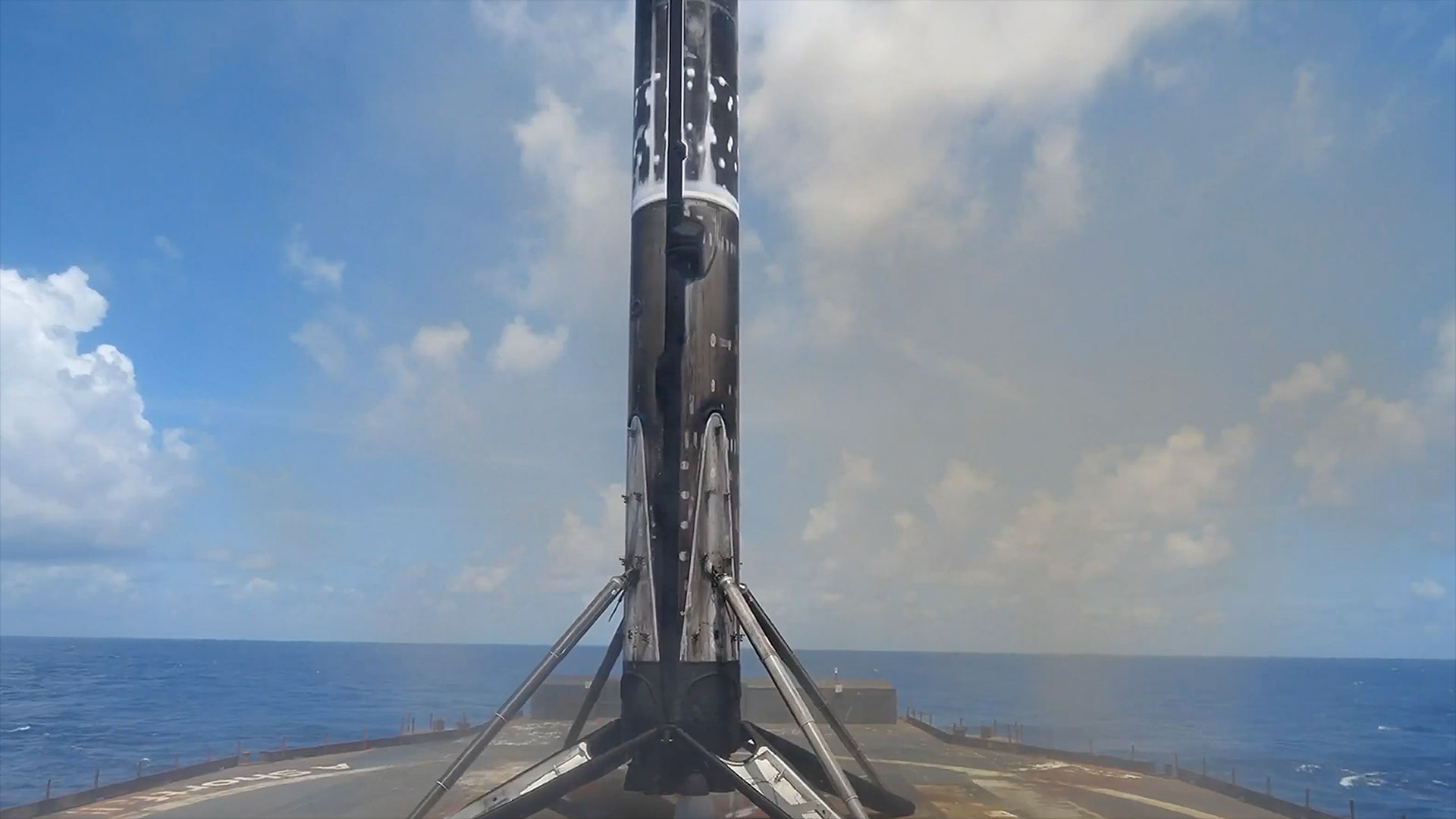 the first stage of a rocket stands on four landing legs atop a sea-based droneship after returning from space