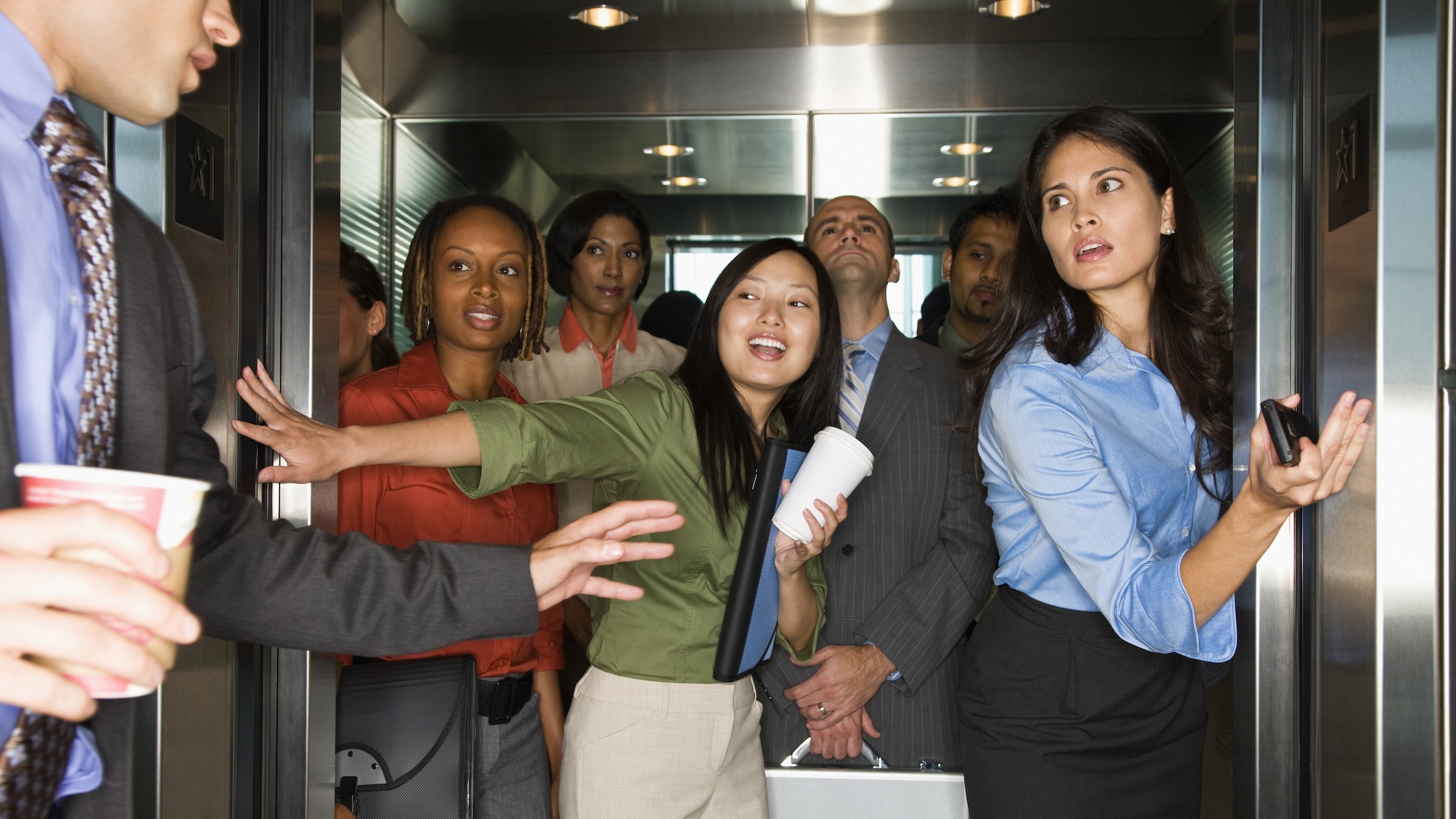 A man rushes to get on a very crowded elevator.