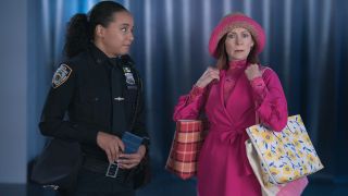 Pictured (L-R): Carra Patterson as Kaya Blanke looking at Elsbeth and Carrie Preston as Elsbeth Tascioni looking shocked while holding three tote bags.