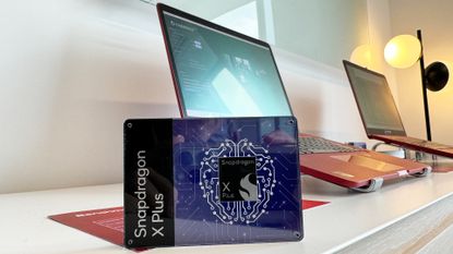 A pair of laptops behind a Qualcomm Snapdragon X Plus chip in a display